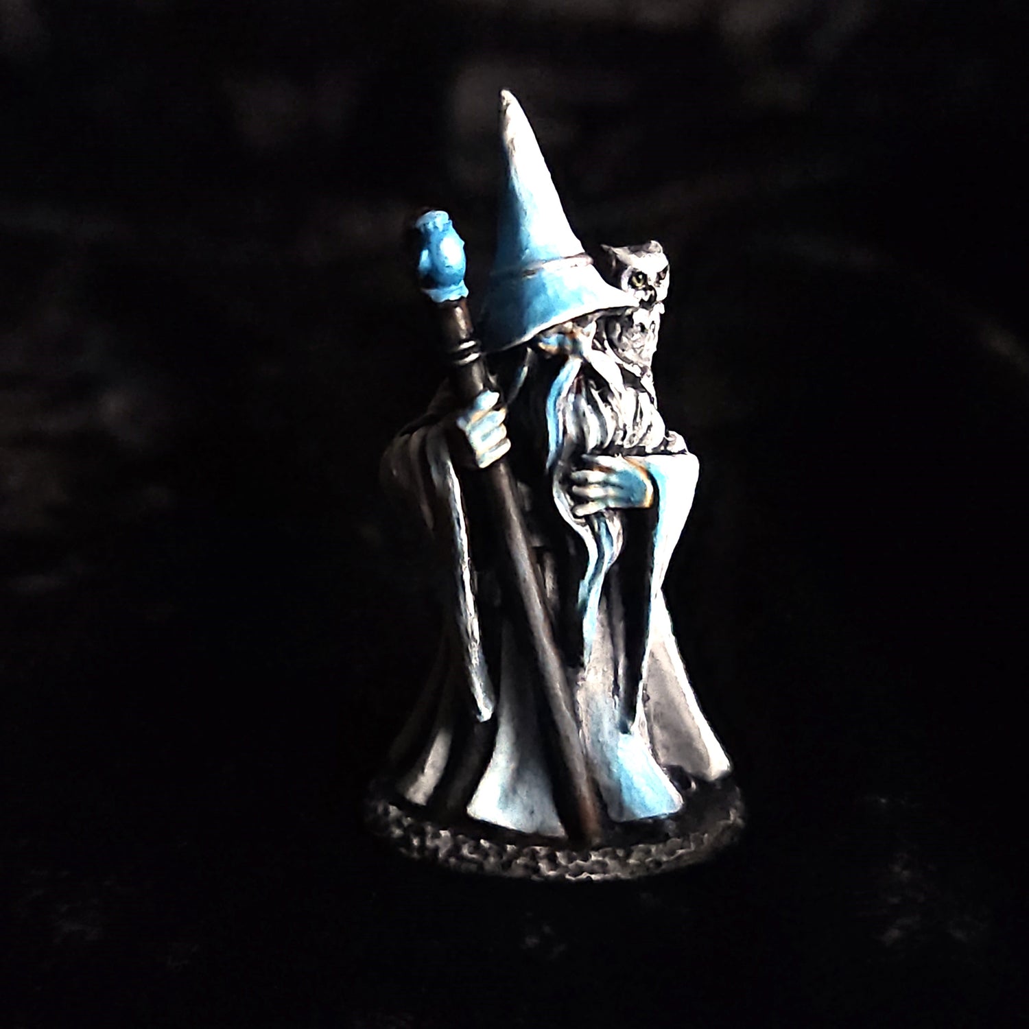Painted wizard miniature figure holding a staff, dark robe with blue highlights