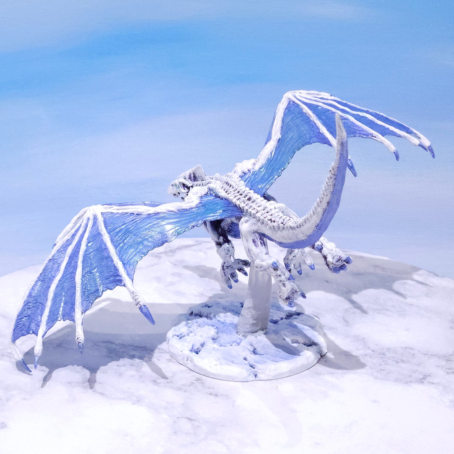 Hand-painted flying White Dragon miniature perched on a custom snowy mountain tabletop environment base by Rose and Shadow.