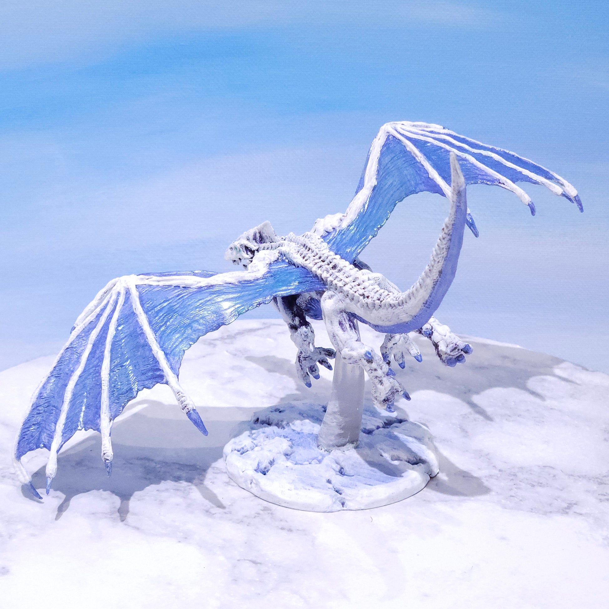 Hand-painted flying White Dragon miniature perched on a custom snowy mountain tabletop environment base by Rose and Shadow.